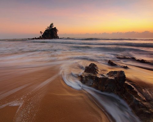 Footsteps on a sandy beach at sunset